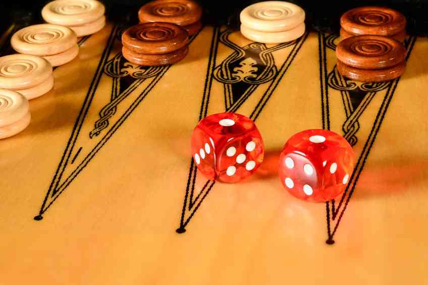 red dice on a backgammon board with checkers